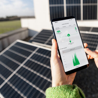 Due mani con smartphone e pannelli fotovoltaici nello sfondo